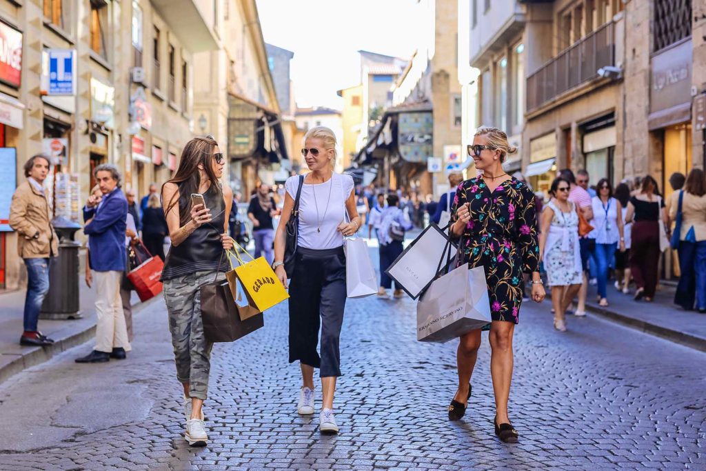 A group of women walking down the street with shopping bags.